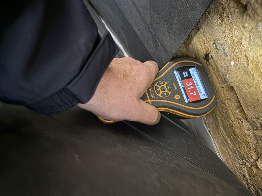 Measuring dampness with a moisture meter.