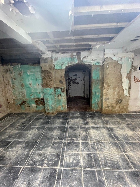 A basement showing water damage on the floor and walls.