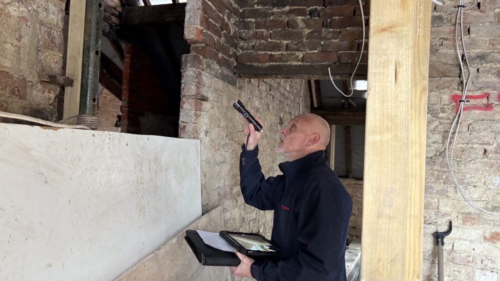 Commercial Structural Repair Surveys in London: What They Include & Why They Save Money 3 A surveyor examining a ceiling void from ground level.