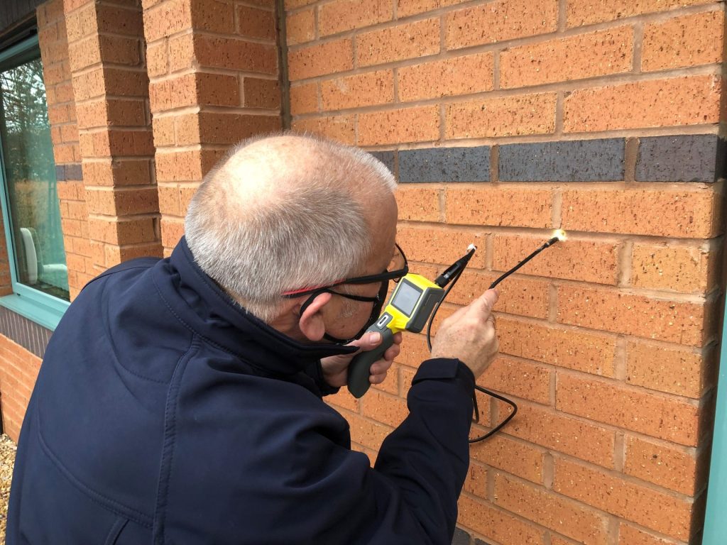 Wall Tie Failure and Structural Damage: What You Need to Know 4 A surveyor inserting a flexible camera into a cavity wall